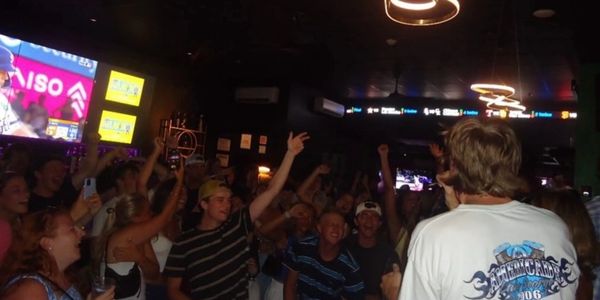 Crowd enjoying a lively music event with a performer on stage.