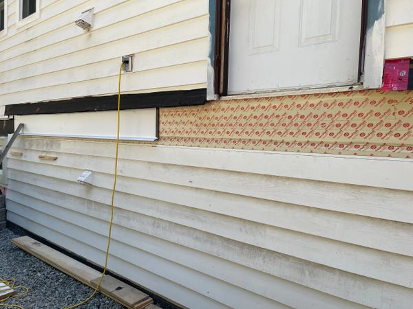 House exterior wall with partial siding removal and exposed insulation.