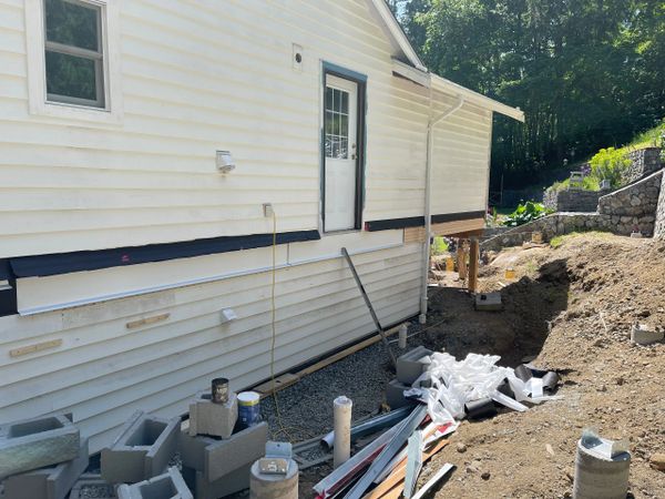 Side of a house under construction with building materials scattered.