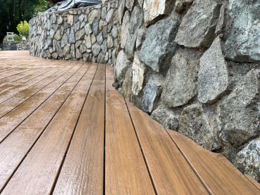 Wooden deck next to a stone wall.
