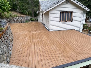 Newly finished wooden deck attached to a white house.