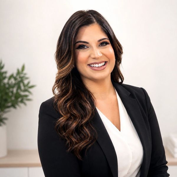 Professional woman with long wavy hair and a black blazer smiling.