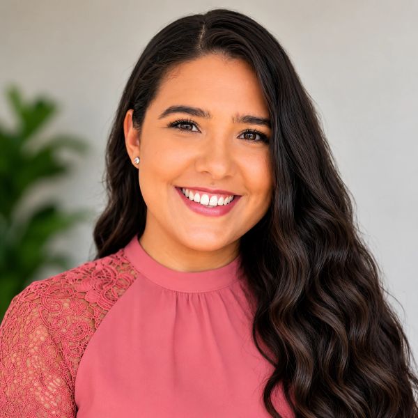 Smiling woman with long dark hair in a pink lace top.