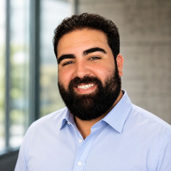 Smiling man with beard in blue shirt.