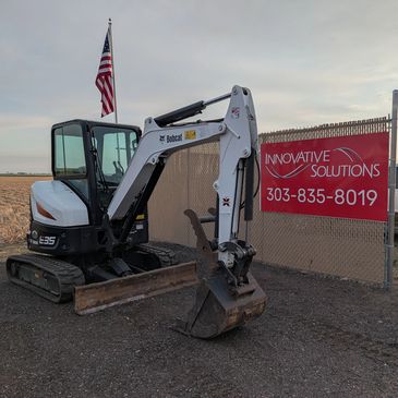 Small Bobcat excavator next to a sign for Innovative Solutions.