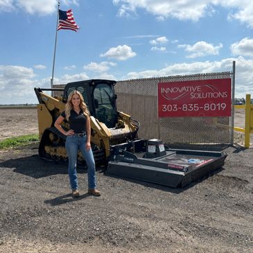 Woman standing near construction equipment and a sign.