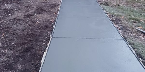 Freshly poured concrete sidewalk with wooden forms on sides.