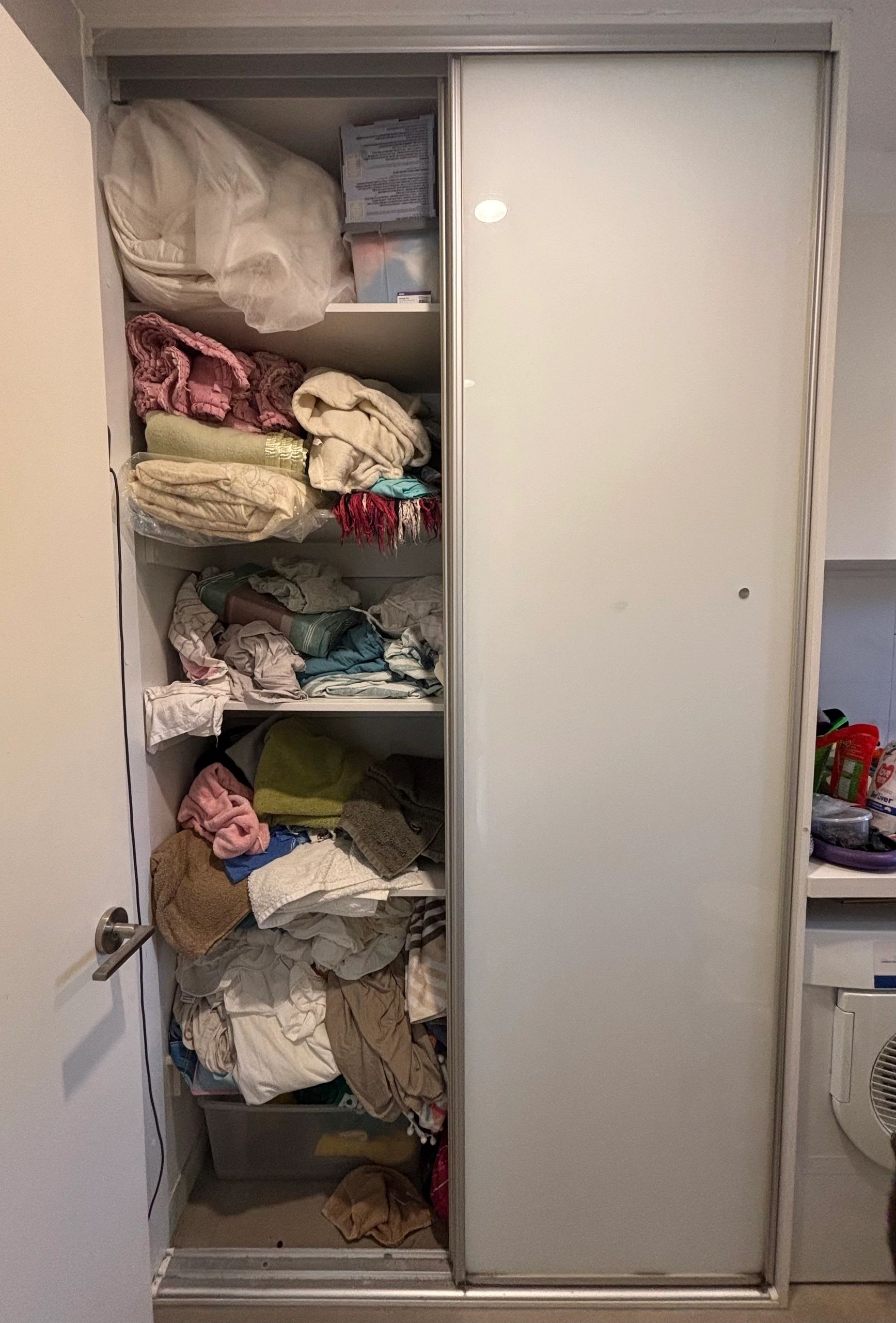 A cluttered linen closet with towels and blankets.