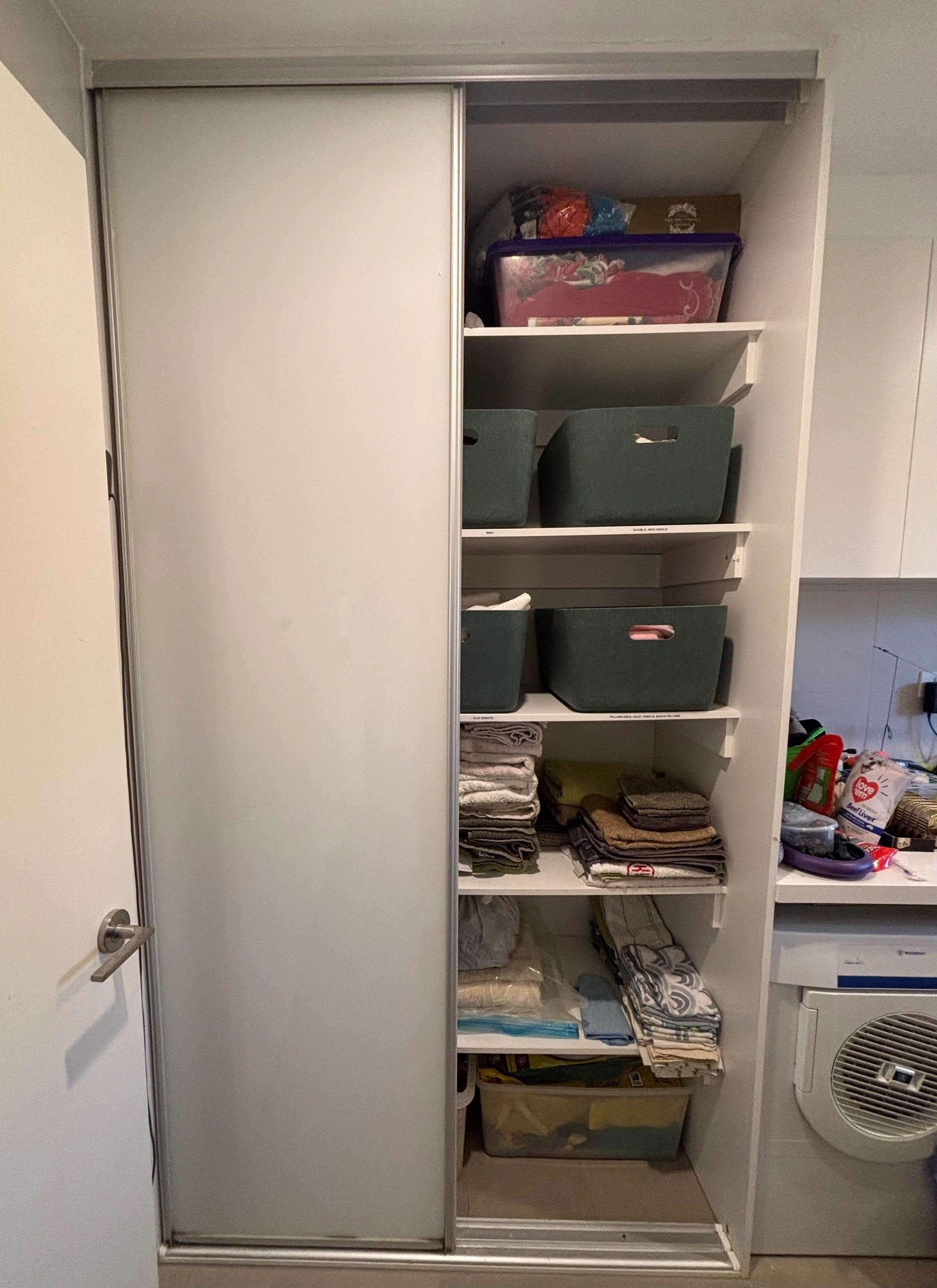 Organized closet with bins and folded linens.