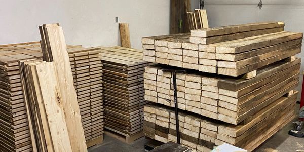 Reclaimed wood flooring and floating shelves in various stages of processing.