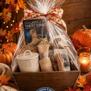 Autumn-themed gift basket with assorted items and pumpkins.