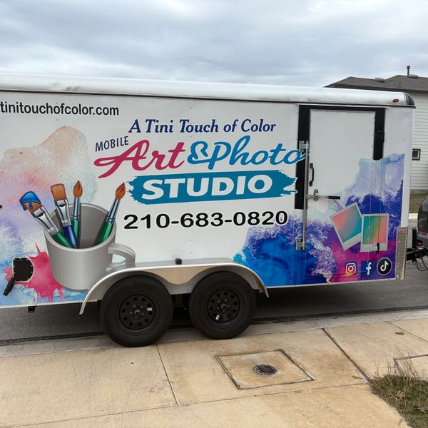 Mobile art and photo studio trailer with colorful design and contact info.