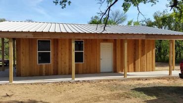 New wooden cabin with metal roof in rural area.