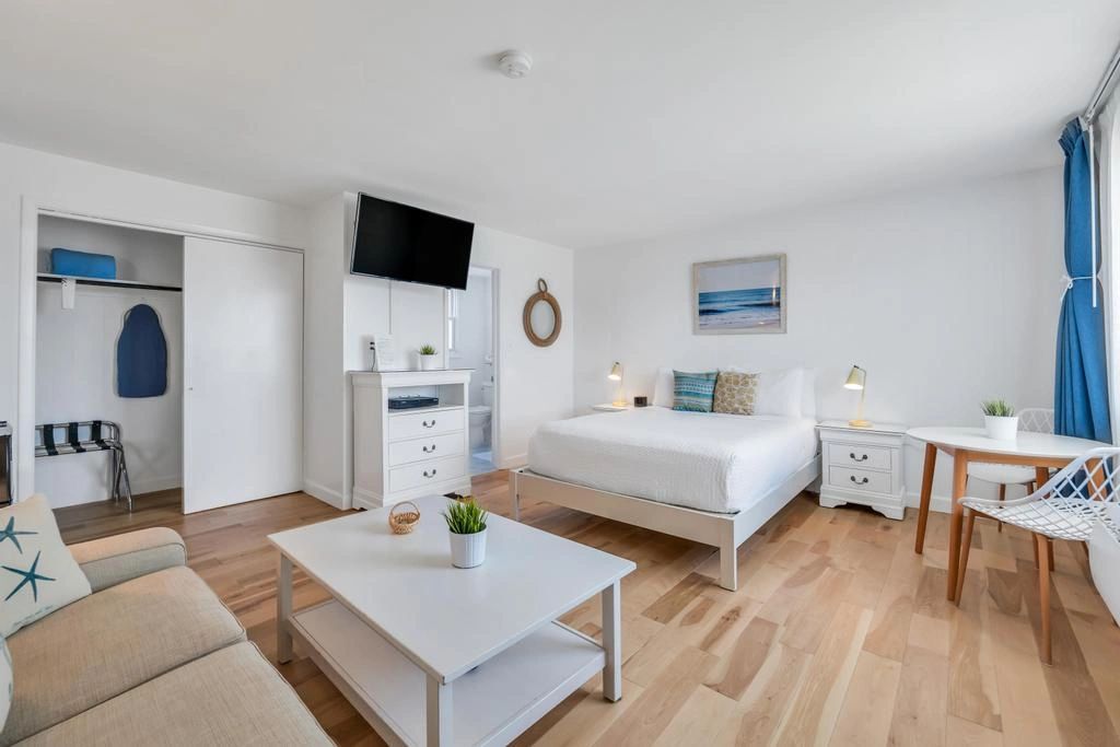 A wide view of a suite with a sofa, coffee table, bed, desk, and TV.