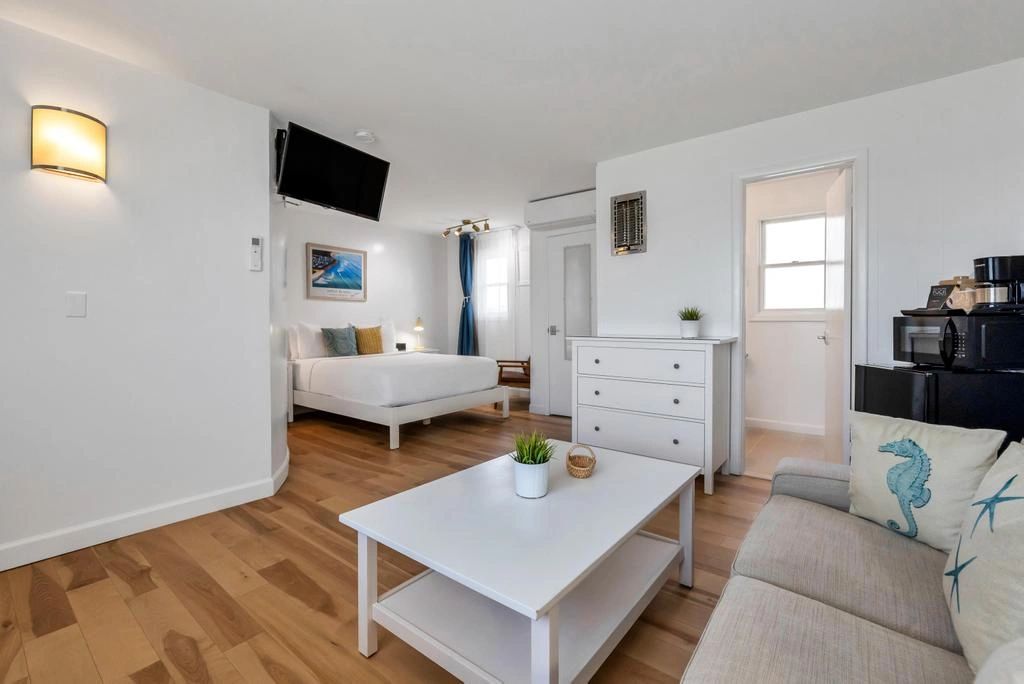 A wide view of a hotel room's living area with a sofa, coffee table, and bed in the background.