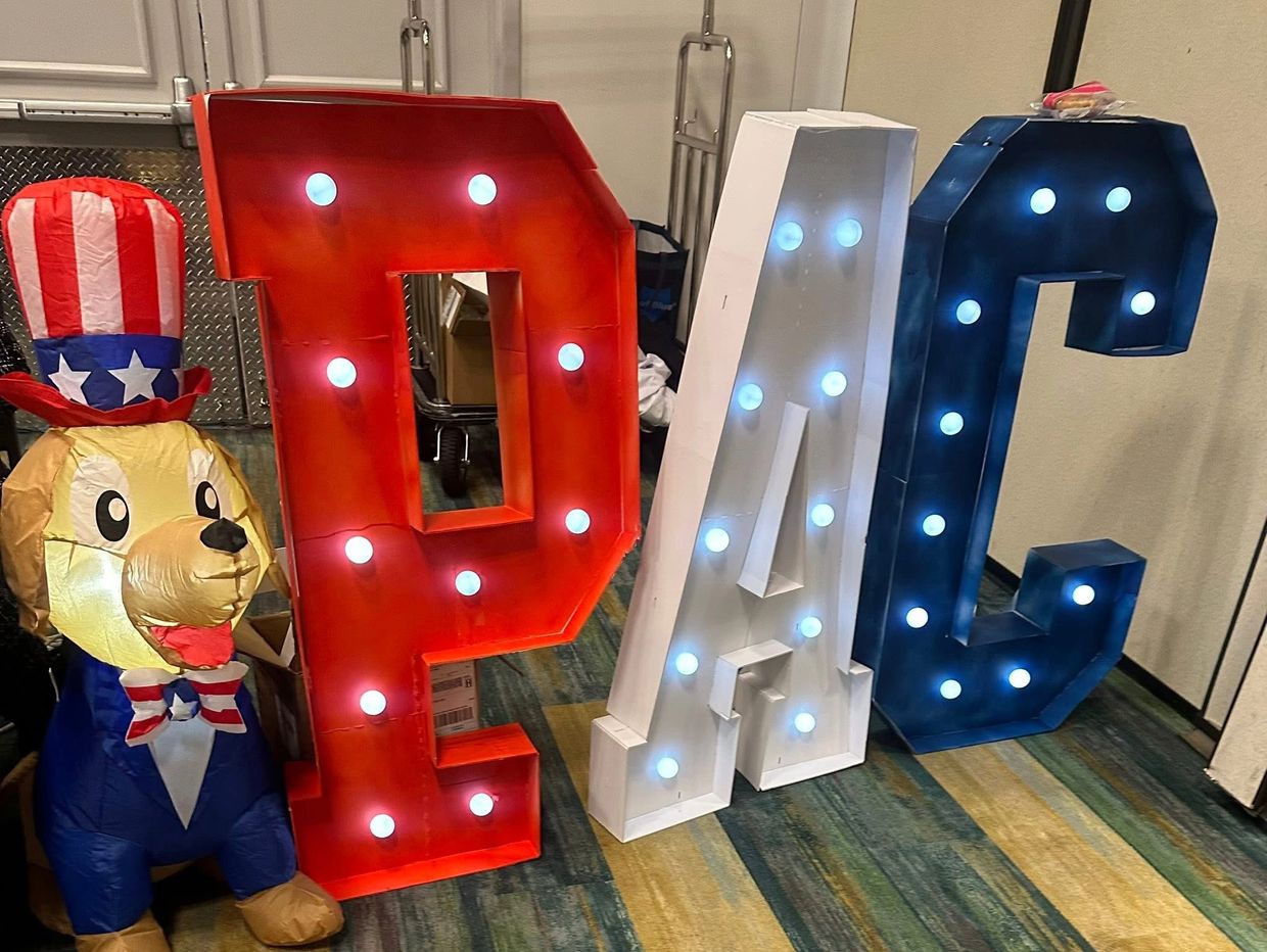 Illuminated red, white, and blue letters "PAC" with a patriotic dog figure.