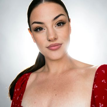 Woman with makeup and red outfit smiling.