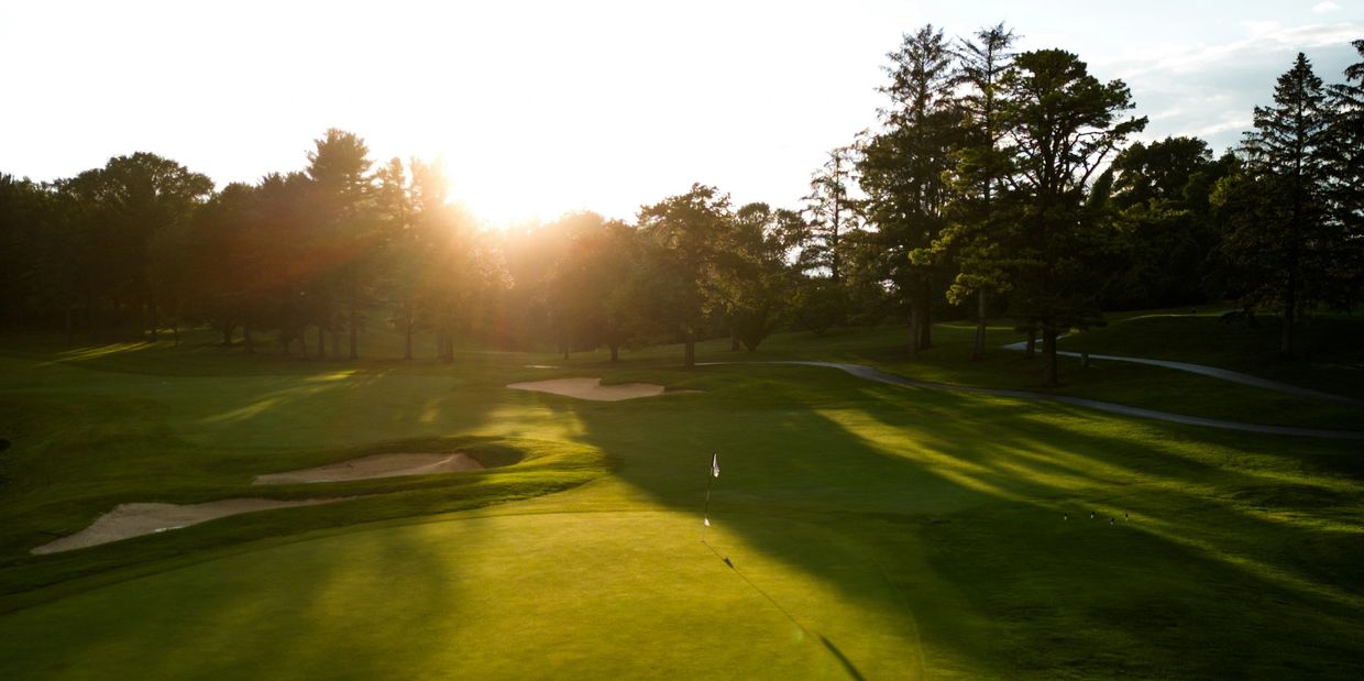 Sunset lighting up a quiet golf course with trees and sand bunkers.