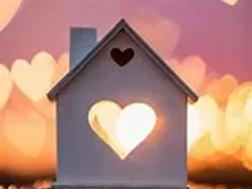 A small house model with heart-shaped cutouts glowing warmly.