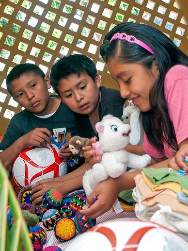 Maya children examine stuffed animals and a soccer ball, during a distribution event.