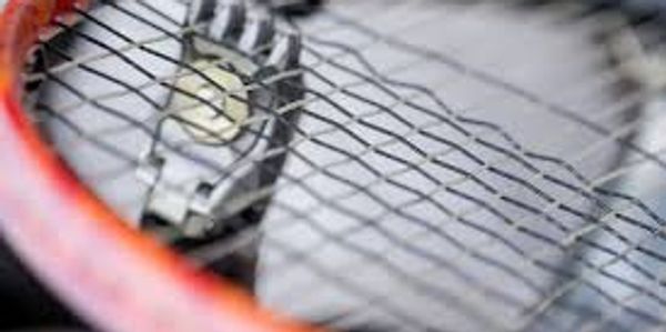 A tennis racket with the net in focus.
