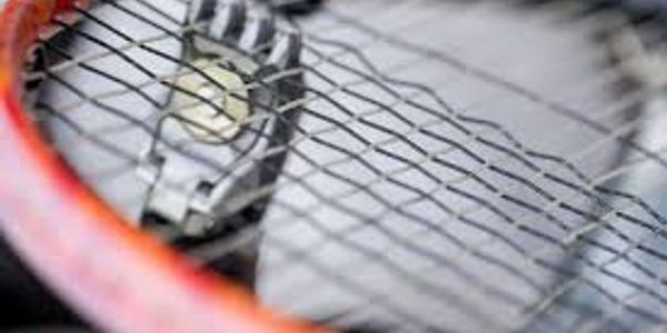 A tennis racket with the net in focus.