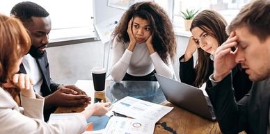 Frustrated colleagues in a tense business meeting reviewing documents.