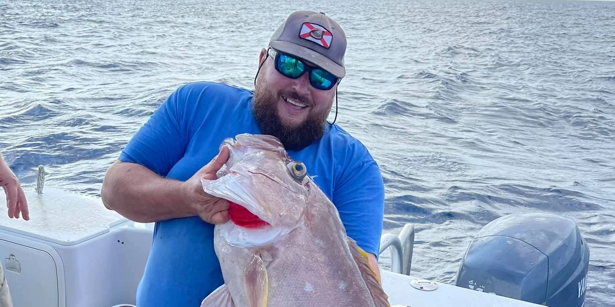 Randall E. Davis II holding a fish on a boat 

