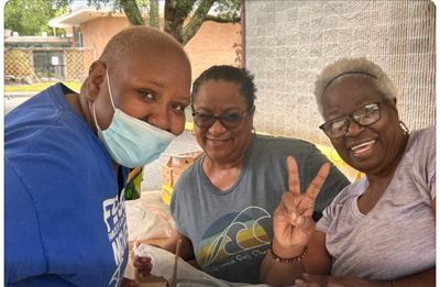 Three women smiling and enjoying a casual outdoor gathering.