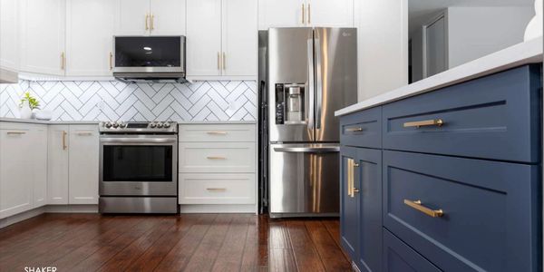 Modern kitchen with white and navy blue cabinets and stainless steel appliances.