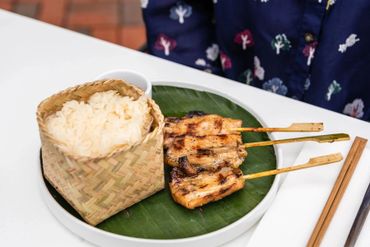 Some rice in a bucket with some sticks in a plate