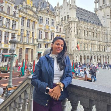 Woman posing near historic buildings in a busy European square.