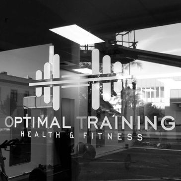Logo for Optimal Training Health &amp; Fitness on a glass door with reflections.