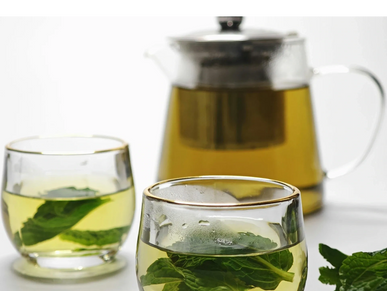 Glass cups and a teapot with fresh mint tea.