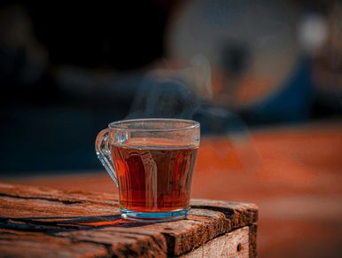 A steaming cup of tea on a rustic wooden surface.