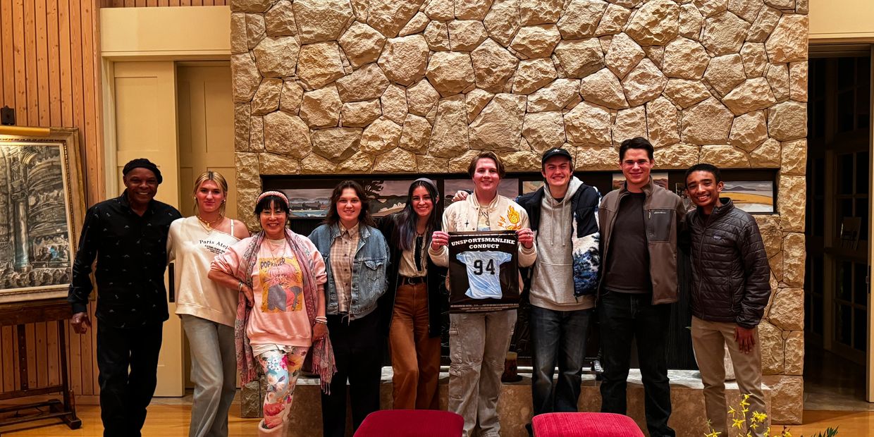 9 members of the cast and crew of "unsportsmanlike conduct" posing with the poster.