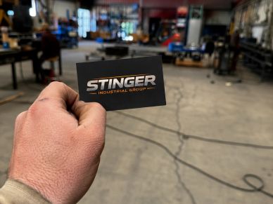 Hand holding a business card in an industrial workshop.