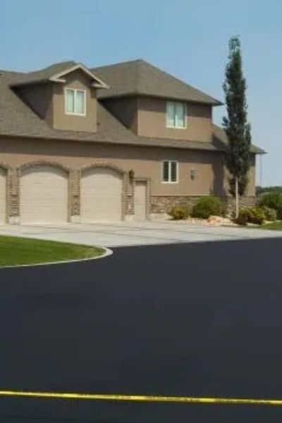 A suburban house with a freshly paved driveway and two garage doors.