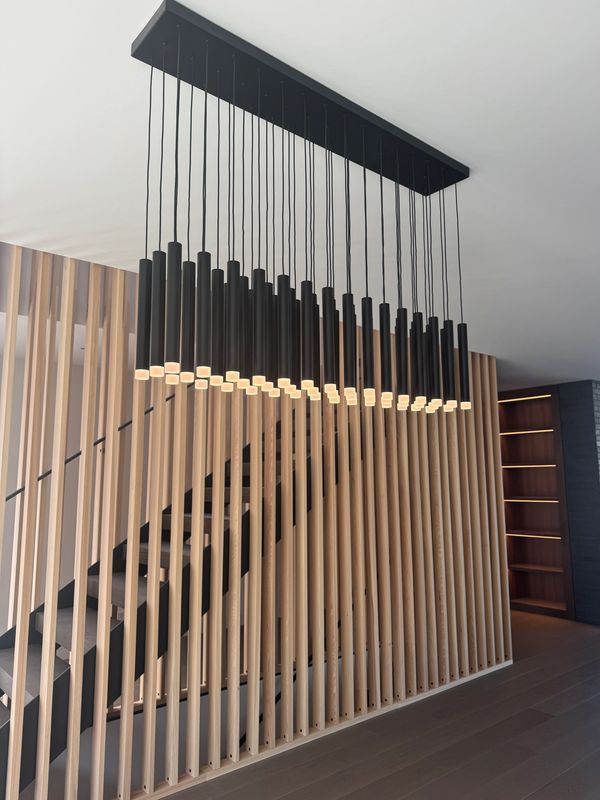 Modern black pendant lights hanging in a room with vertical wooden slats.