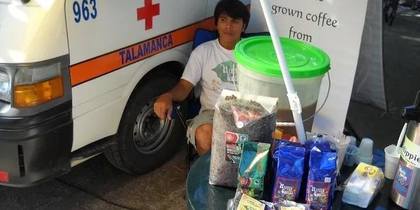 A vendor sells various coffee products in front of an ambulance,