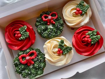 Festive Christmas cupcakes decorated with holly and wreath designs.