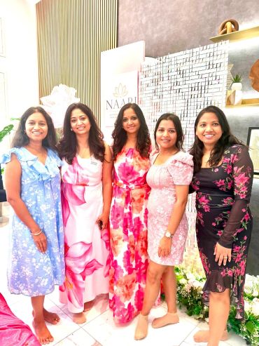 Group of five women in floral dresses posing.