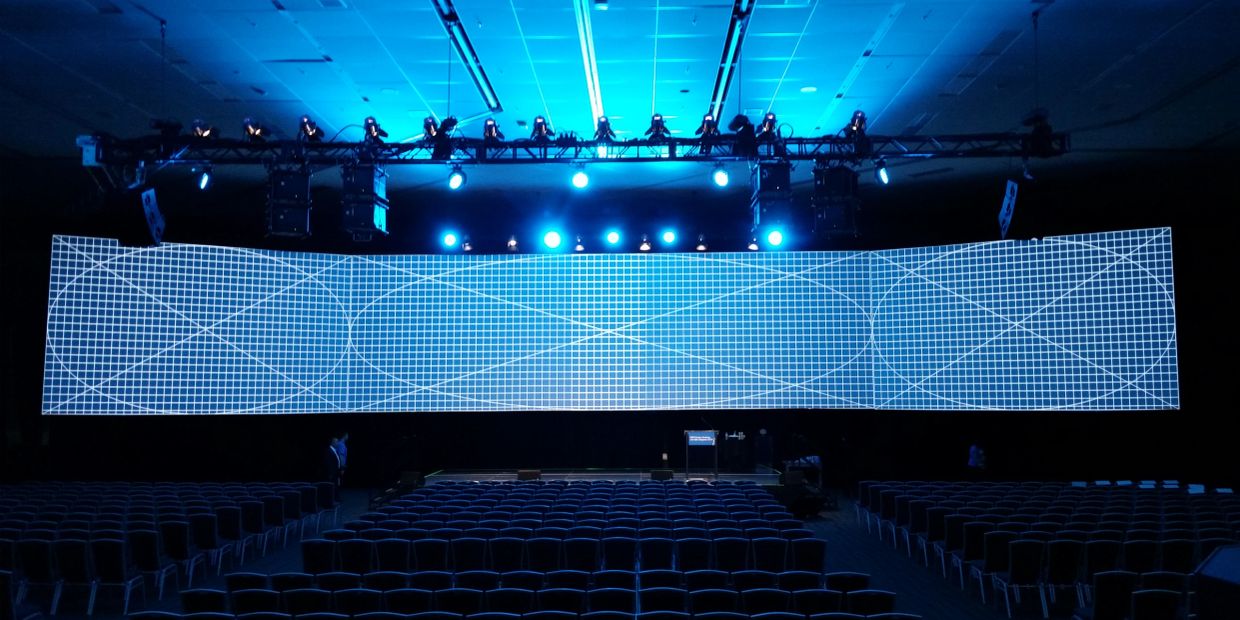 Large curved LED screen in a dark auditorium.