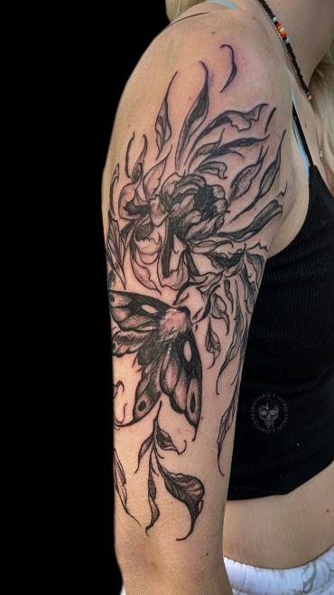 Black and gray floral and moth tattoo on upper arm.