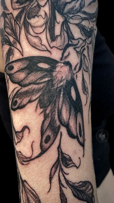 Black and gray moth tattoo with floral designs.