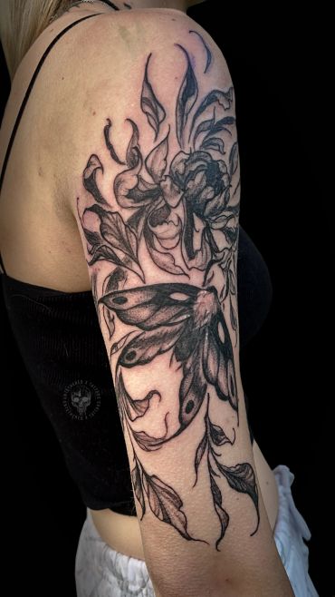 Black and gray floral and moth tattoo on upper arm.