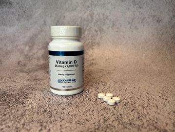 bottle of vitamin D pills next to a pile of the pills 