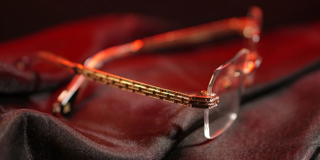 Close-up of elegant eyeglasses with gold frames on dark fabric.