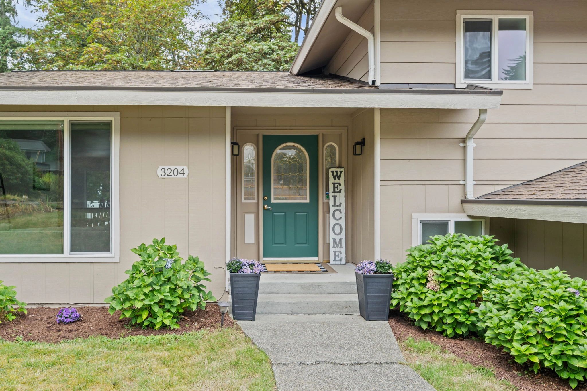 Green door with welcome sign at house entrance.