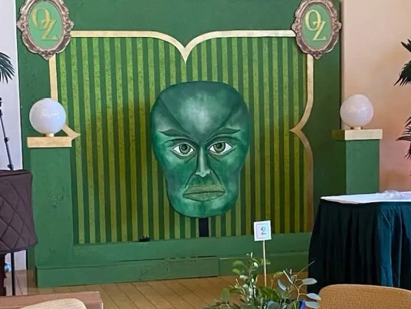 Green wall decoration with a large face and OZ symbols.